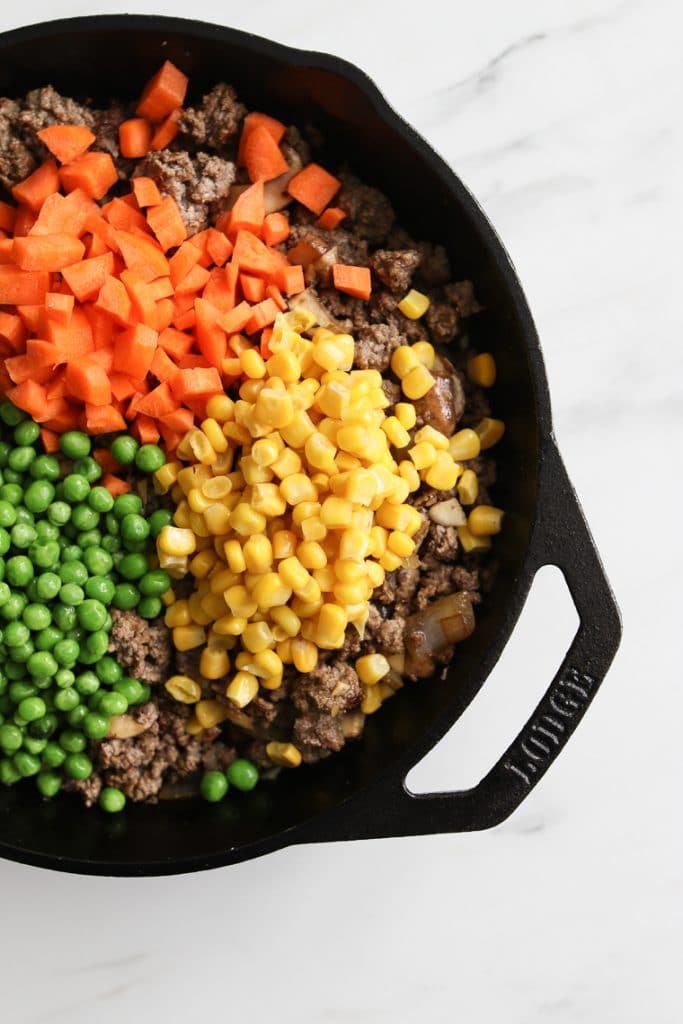 Diced carrots, corn, and peas added the cast iron skillet with browned beef for Beef Shepherd's Pie