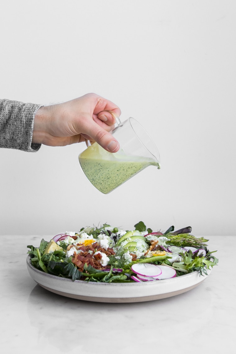 Pouring Green Goddess Dressing on a Salad