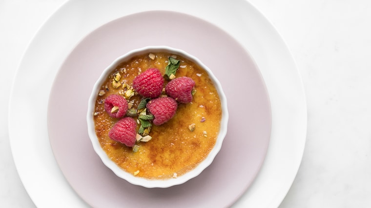 Close up of Coconut Creme Brûlée topped with Raspberries on a Pink Plate