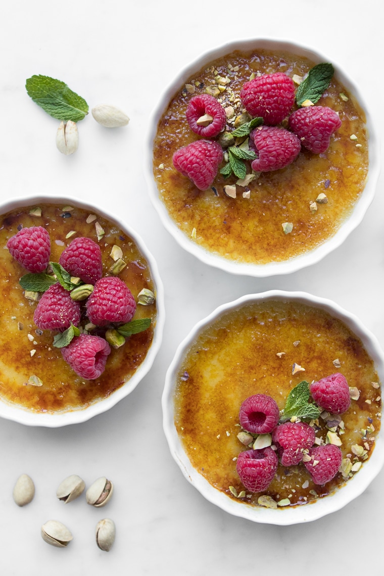 Close up of Three Coconut Creme Brûlées topped with Raspberries