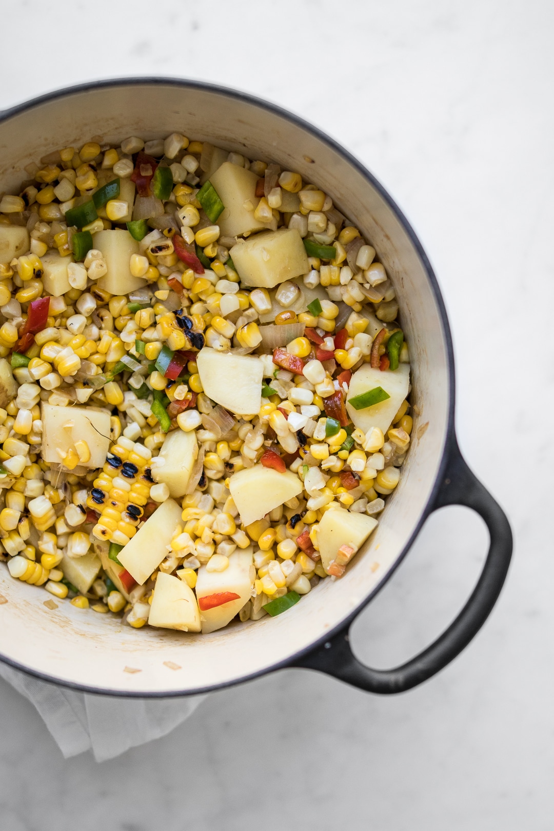 Corn, potatoes, and vegetables cooking in a dutch oven