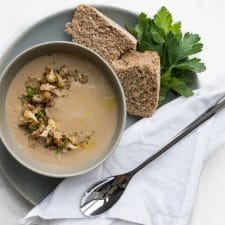 Cauliflower Soup on a plate with bread, a white napkin, and a spoon