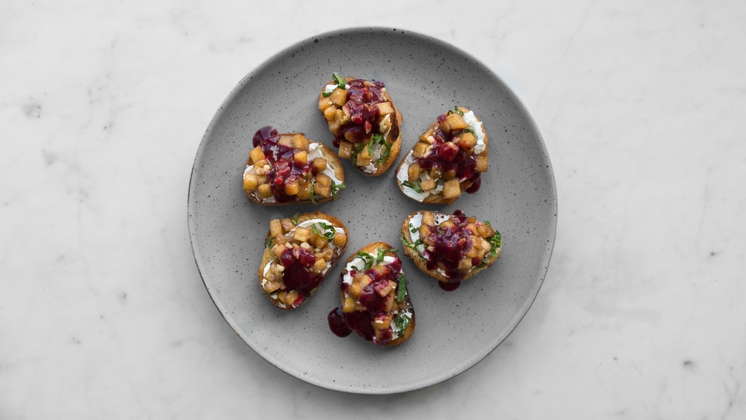 6 crostini topped with apples, cheese and berry sauce