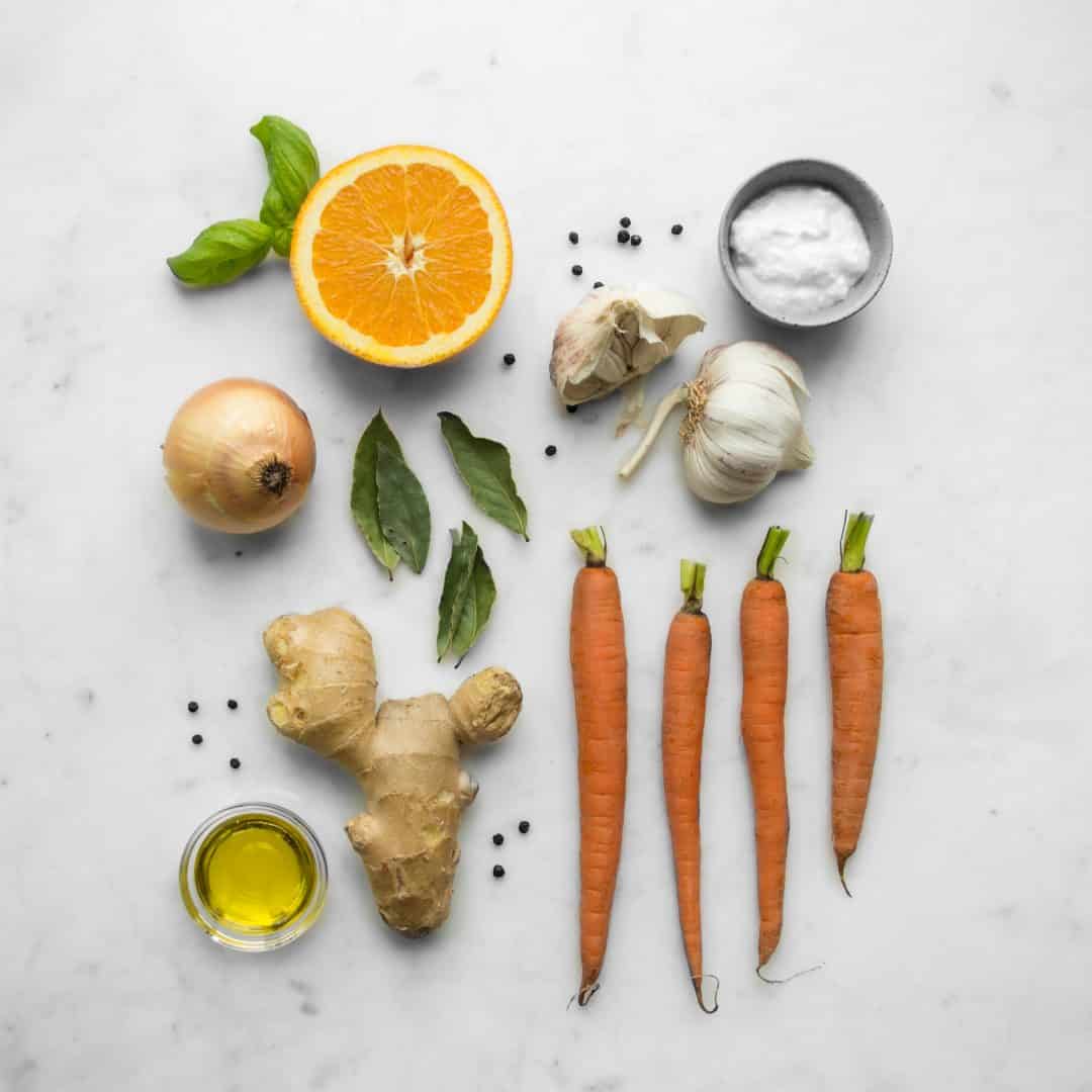 Ingredients for Carrot and Orange Soup - Orange half, basil, carrots, ginger, garlic, onion, olive oil, peppercorns and yogurt