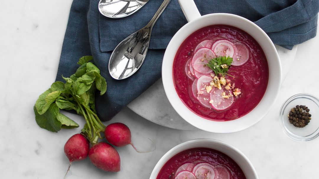 Beet Soup in White Bowl on top of Blue Napkin with Spoons