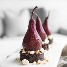 Close up of a Port Poached Pear on a round piece of Chocolate cake with blue cheese on top