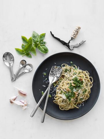 Pesto carbonara on a black plate with basil and garlic