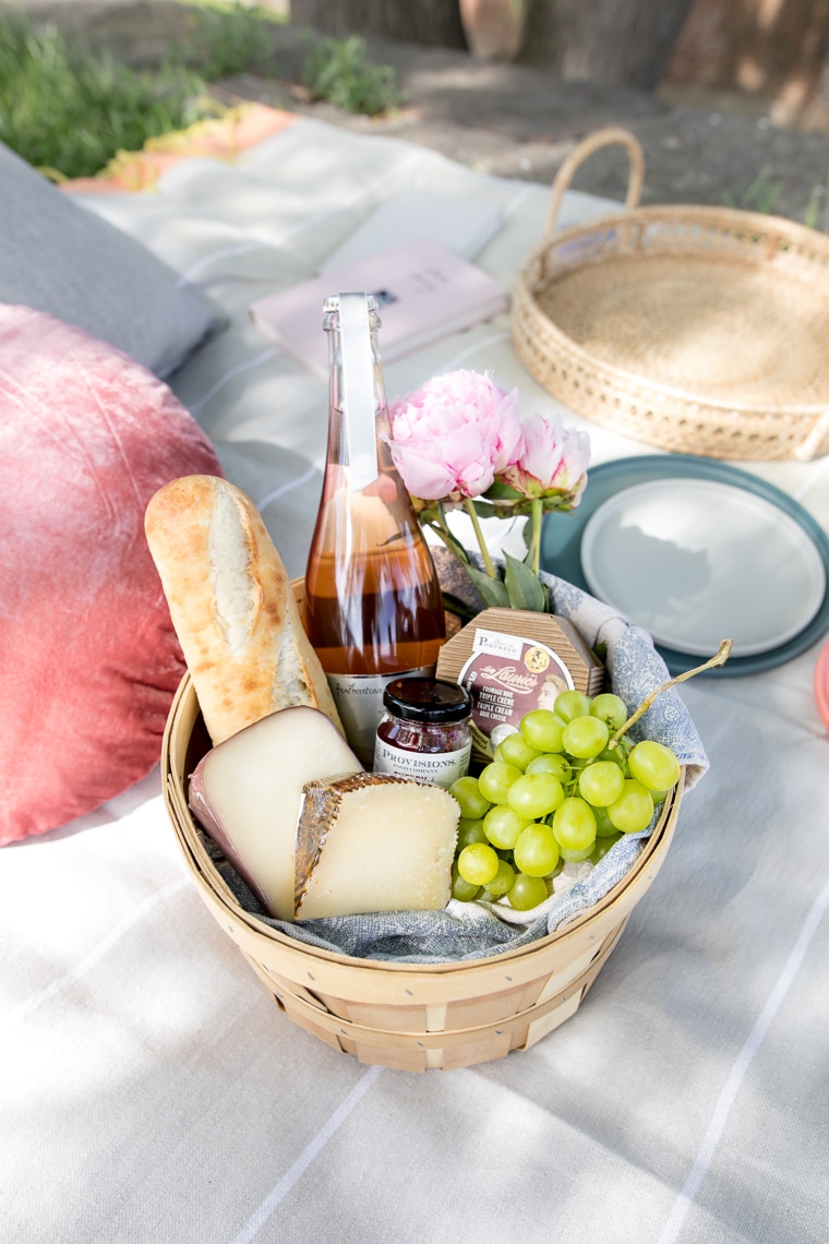 Basket with cheeses, grapes, baguette, jelly and rose champagne