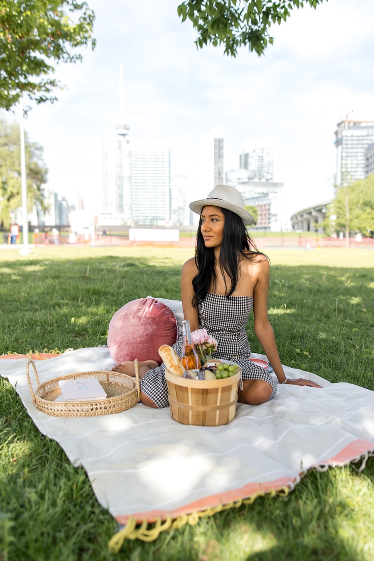 Female sitting on a picnic blanket with basket of food