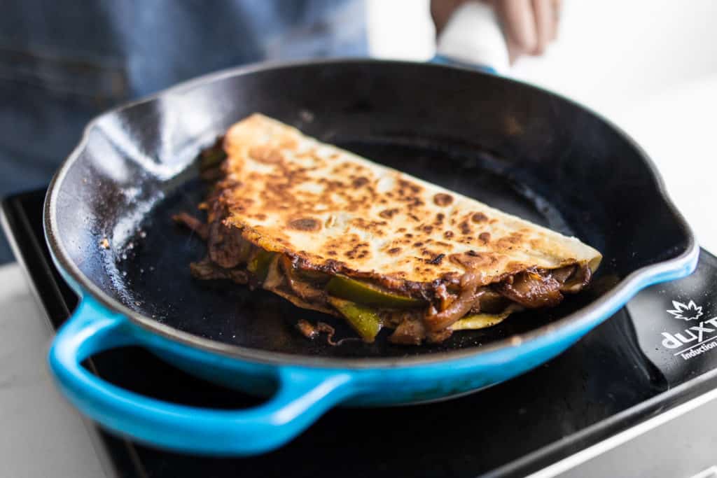 Quesadilla Frying in a Blue Cast Iron Skillet