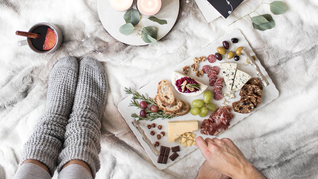 A mug of mulled wine and a comforting cheeseboard on a blanket