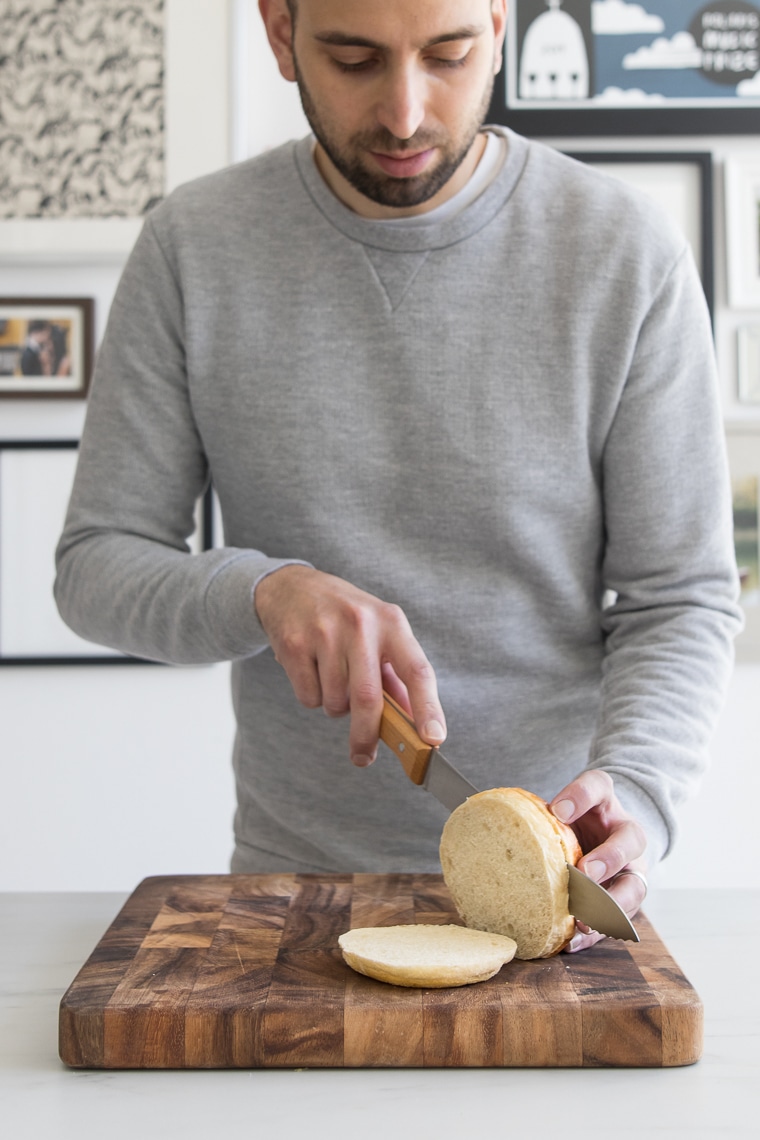 Männchen schneidet ein Hamburger-Brötchen in drei Scheiben