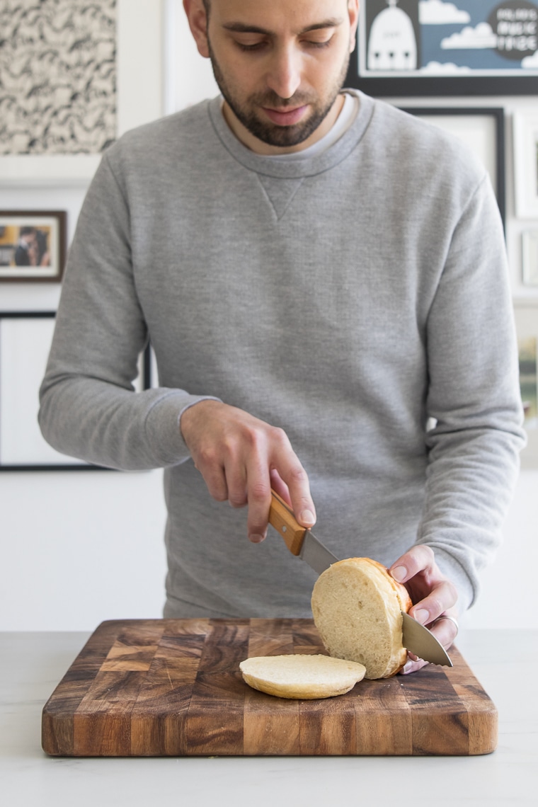 Male slicing a hamburger bun into three slices