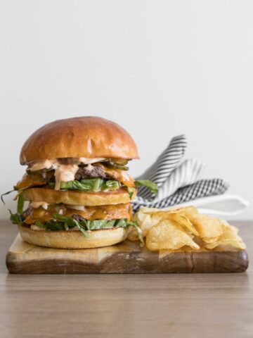 Homemade Big Mac on a wooden board with chips