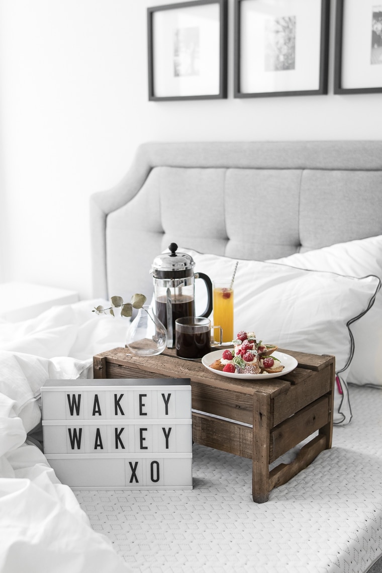 "Wakey Wakey XO" on small cinema sign laying on an Endy mattress with a cup of coffee, french toast, a newspaper, and two Endy pillows