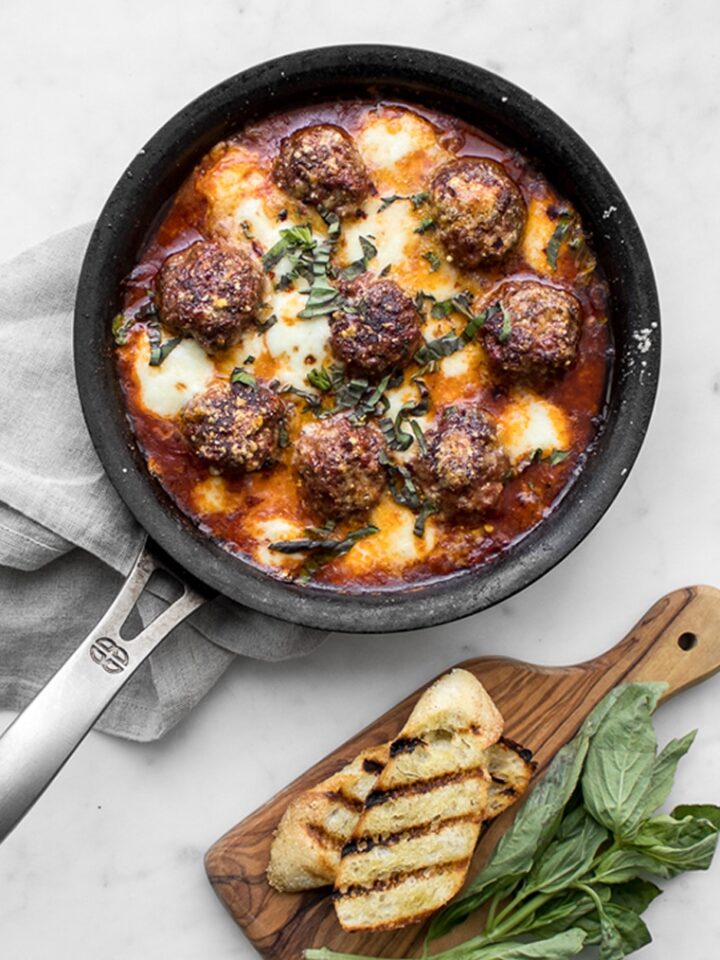 Skillet of Meatballs with cheese, tomato sauce, grilled bread and fresh basil