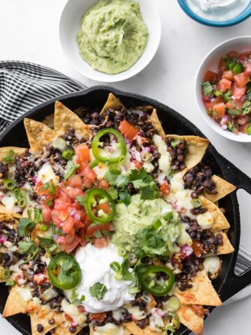 Loaded Nachos with Lentils in a Black Skillet with Guacamole, Sour Cream and Salsa