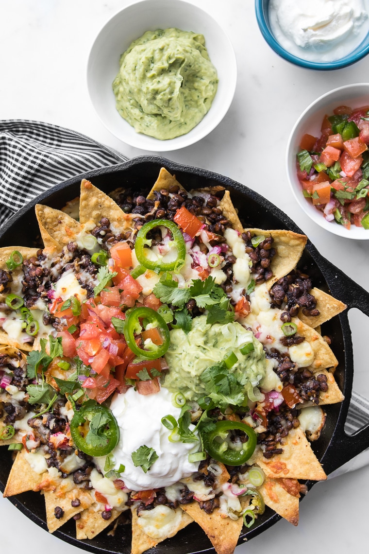 Loaded Nachos with Lentils in a Black Skillet with Guacamole, Sour Cream and Salsa