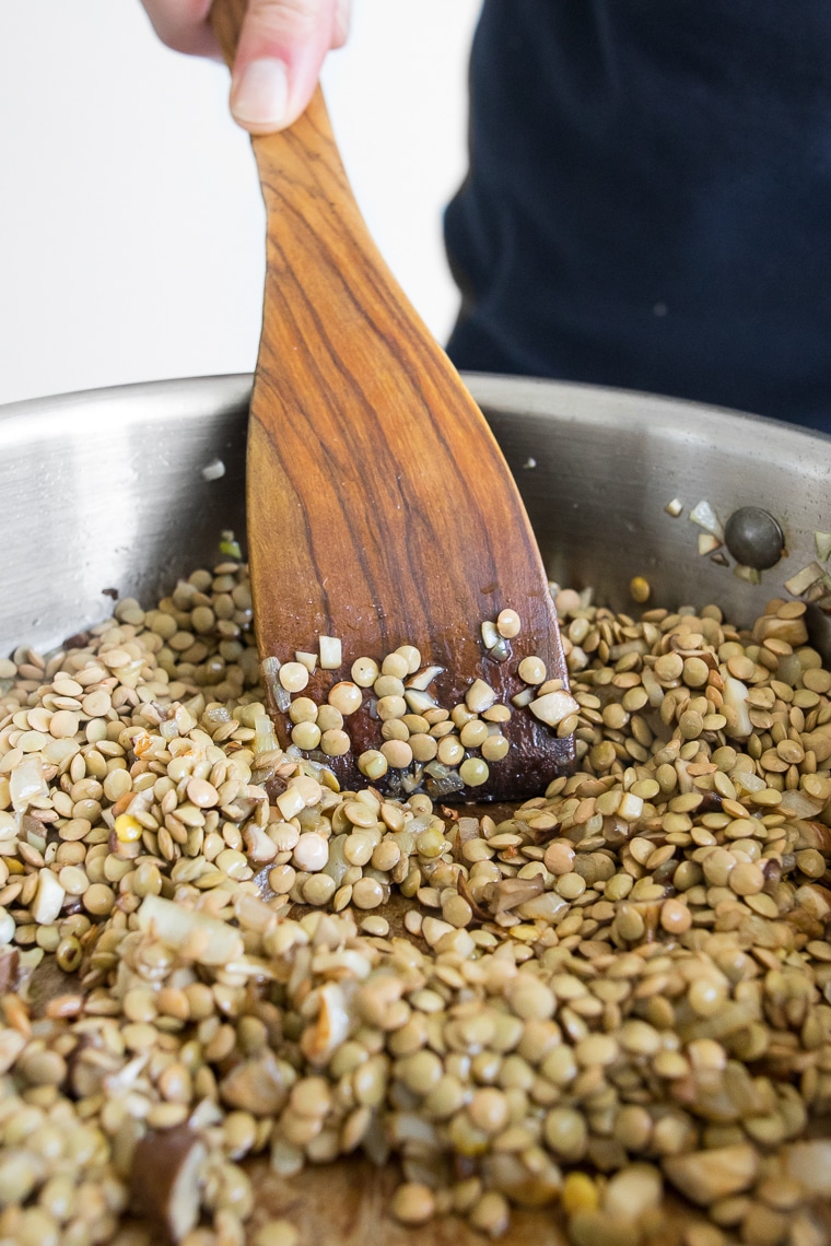 Stirring green lentils in a skillet