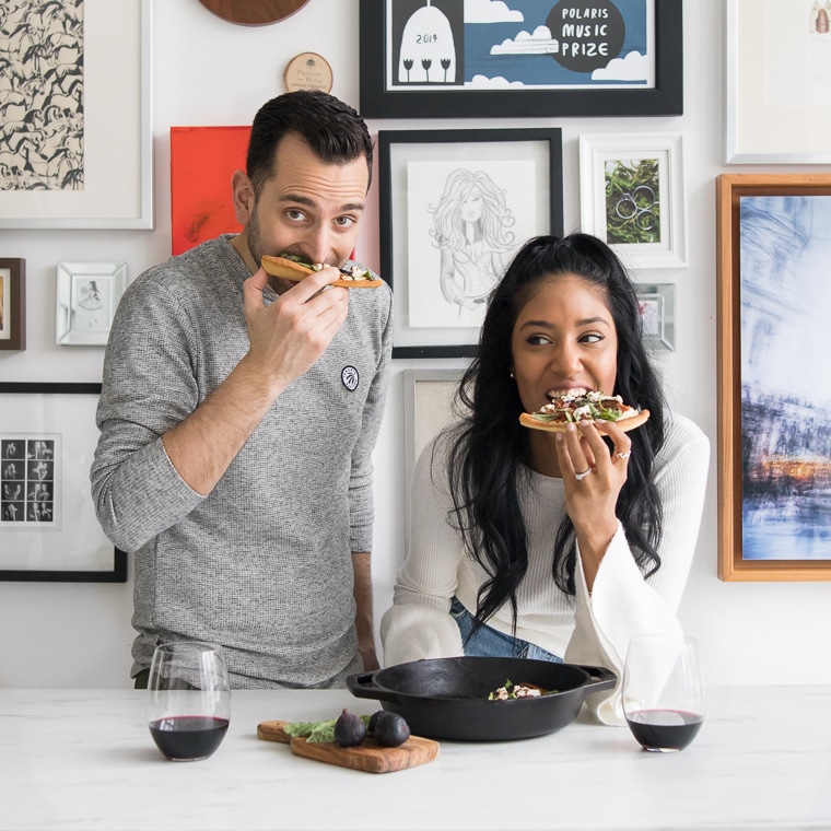 Philip and Mystique eating the prosciutto pizza in front of a gallery style wall