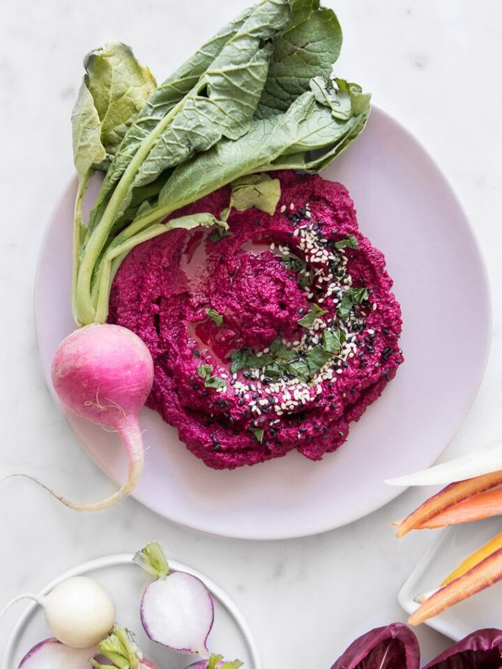 Close up of Roasted Cauliflower and Beet Hummus on a Pink Plate with a Fresh Raddish