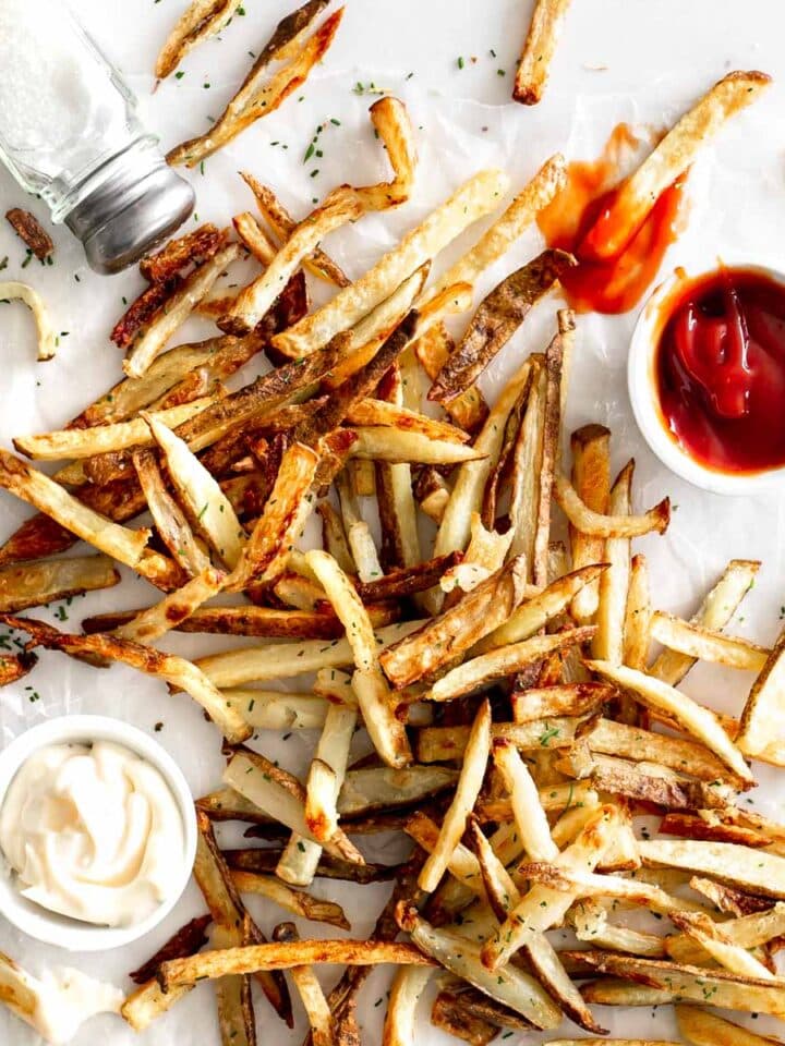 Crispy Oven Baked French Fries on marble with ketchup, mayo and salt