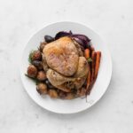 Whole Roast Chicken with Roasted Potatoes, Onions, and Carrots on a Large Round Plate with