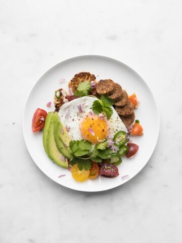 Roasted Cauliflower Steak “Huevos Rancheros” on a white plate