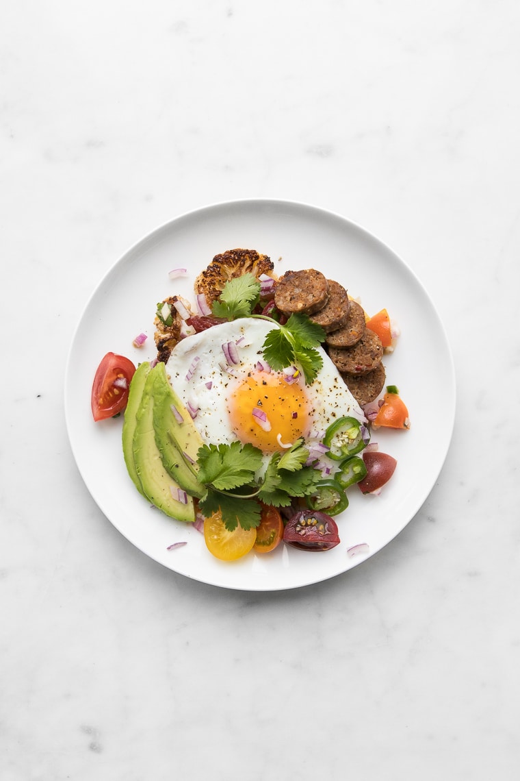 Roasted Cauliflower Steak “Huevos Rancheros” on a white plate