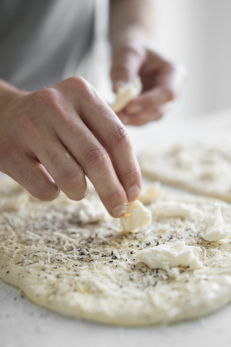 Topping pizza dough with mozzarella cheese