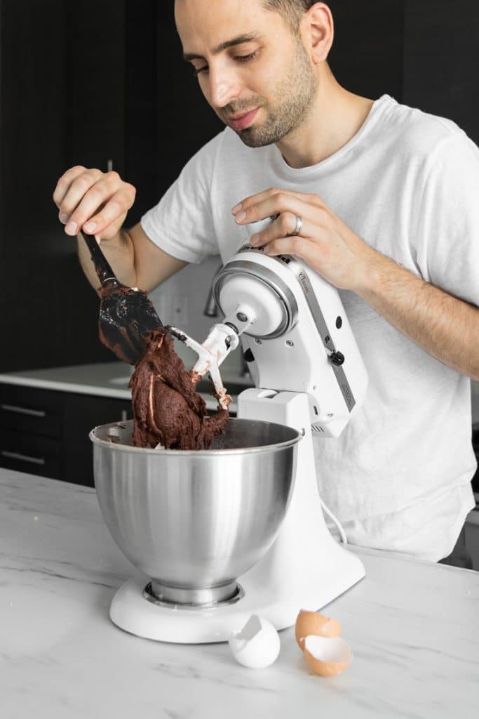 Guy in white shirt scraping beater of kitchen-aid mixer