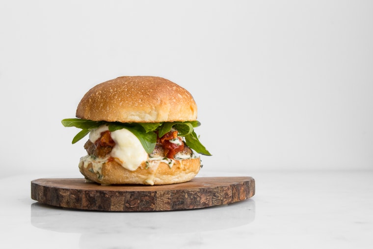 Our BBQ Parmigiana Pork Burgers are topped with mozzarella, tomato sauce & basil mayo. Each bite releasing a burst of flavour for one fancy (and messy) Italian burger. Get the recipe at chefsouschef.com #recipe #bbq #pork #parmesan #tomatoes #basil #burger #summer #foodstyling #foodphotography #chefsouschef