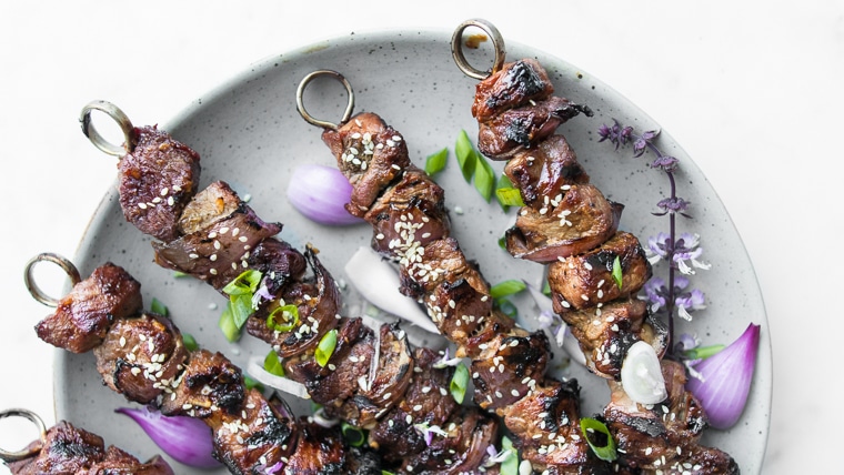 Close up of BBQ Beef Kebabs on a plate with red onions