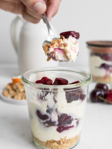 Holding a spoonful of bourbon cherry cheesecake in a jar