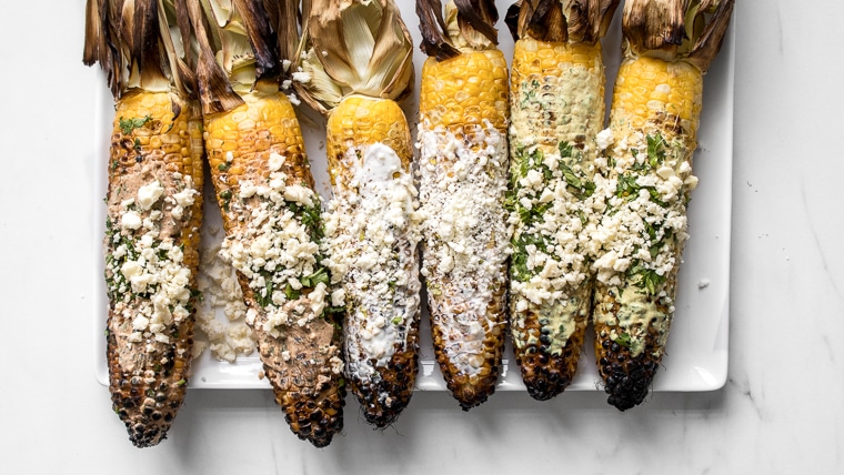 A plate of grilled street corn with husks attached served 3 different ways