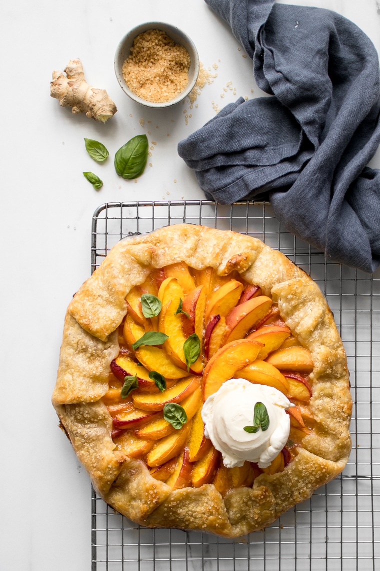 Peach galette cooling on a wire rack with a scoop of ice cream