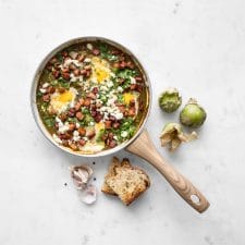 Green shakshuka in a pan with tomatillos and bread
