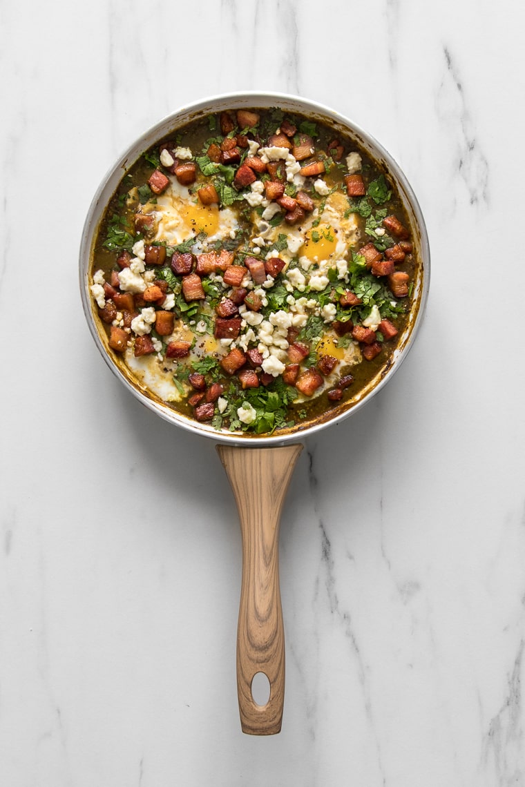 Green shakshuka with Tomatillo sauce in a white skillet