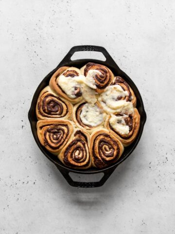 Baked chocolate rolls in a skillet with cream cheese frosting