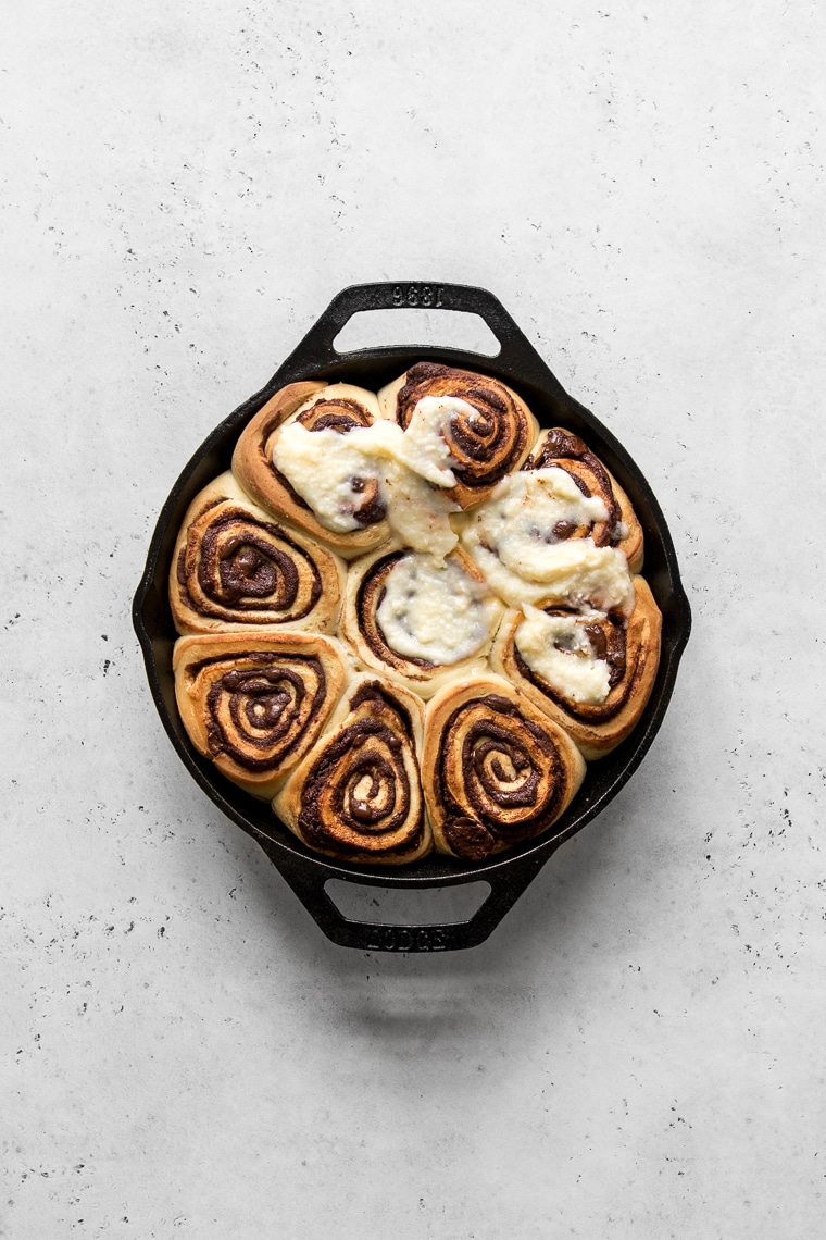 Baked chocolate rolls in a skillet with cream cheese frosting