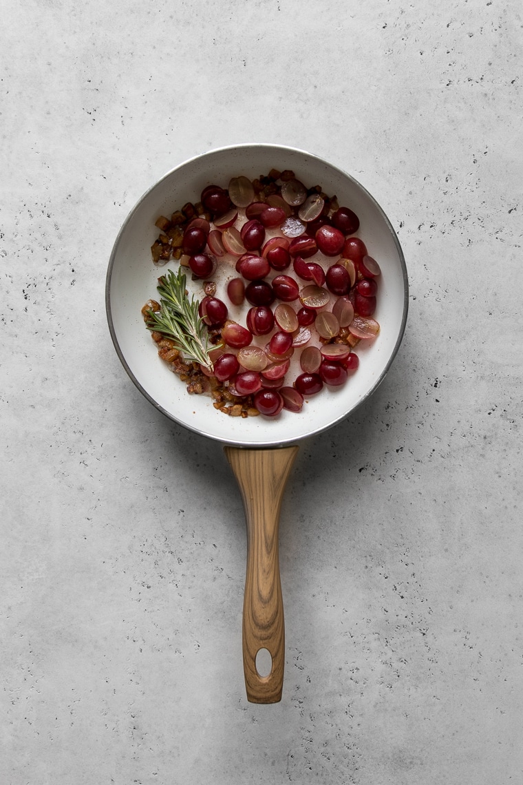 Grapes, rosemary and pancetta in a white frying pan