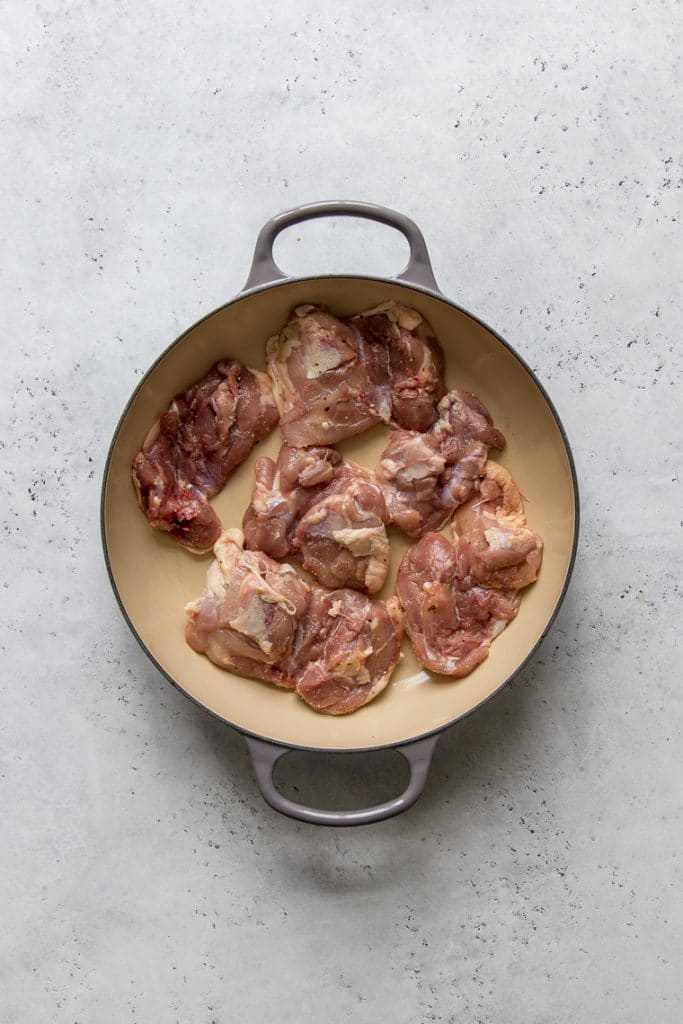 Raw chicken thighs in a Le Creuset braiser
