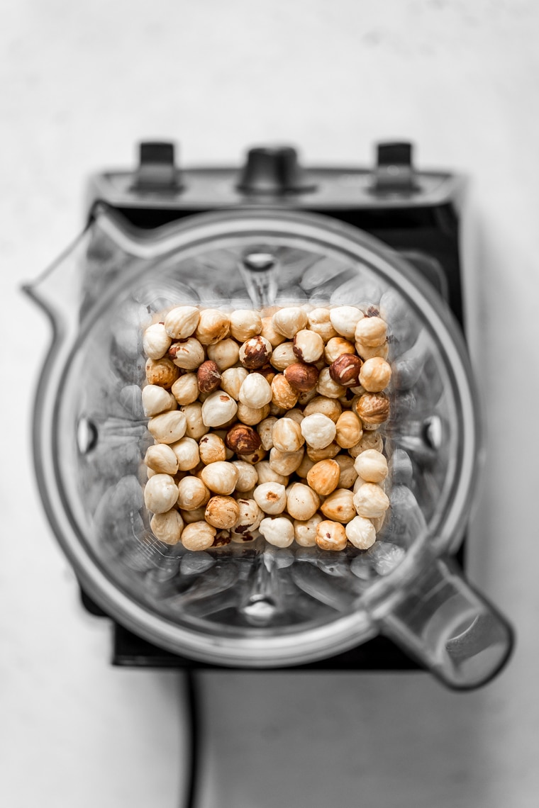 Overhead view of roasted hazelnuts in a blender container