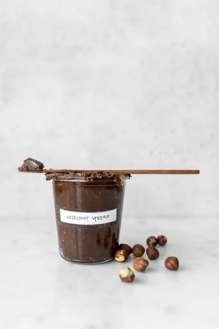 Side view of homemade chocolate hazelnut spread in a mason jar with hazelnuts