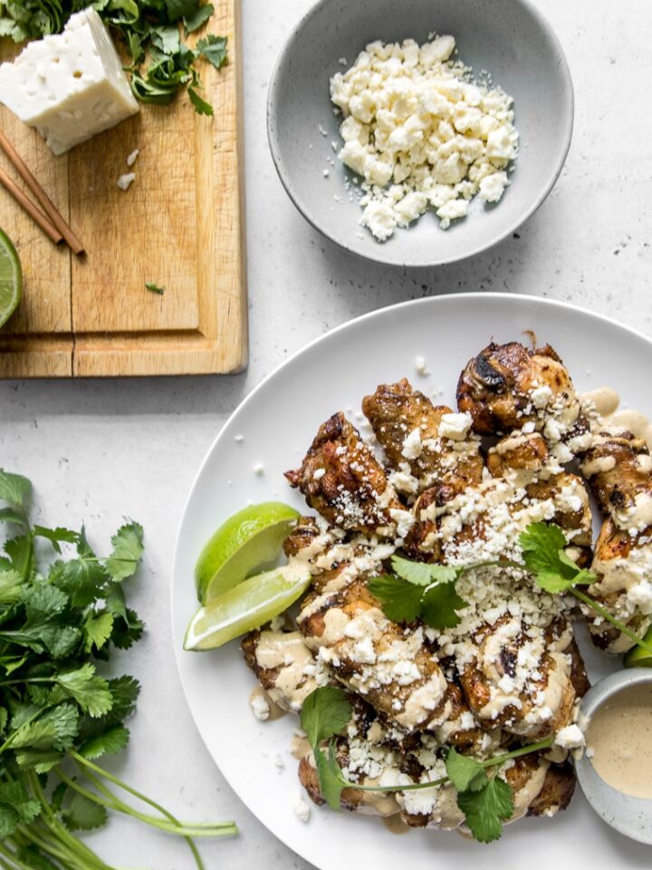 Chicken wings with sauce and crumbled cheese, cilantro and lime wedges