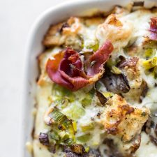 Close up of breakfast casserole with mushrooms and leeks with prosciutto on top