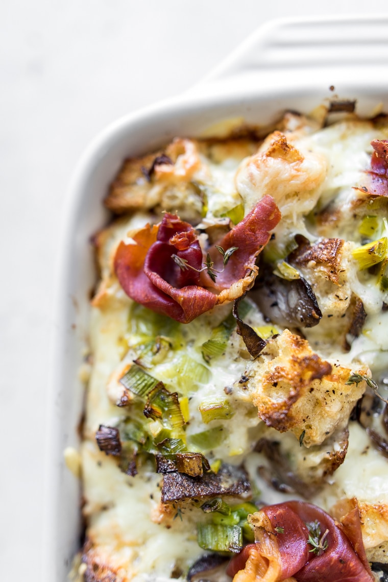 Close up of breakfast casserole with mushrooms and leeks with prosciutto on top