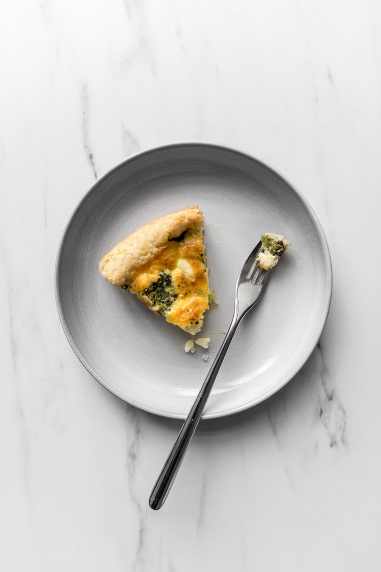 A slice of broccoli and cheese quiche with a bite taken out