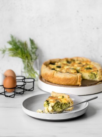 Broccoli and Goat Cheese Quiche with Slice on a Grey Plate