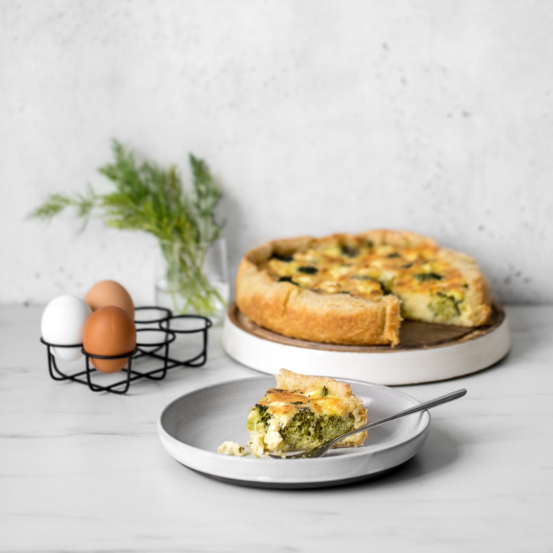 Broccoli and Goat Cheese Quiche with Slice on a Grey Plate